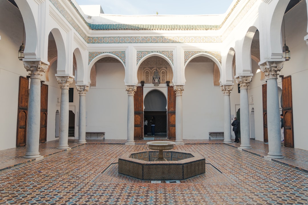 Pourboire dans un riad marocain — membre du personnel portant les bagages d'un client dans une cour carrelée de riad