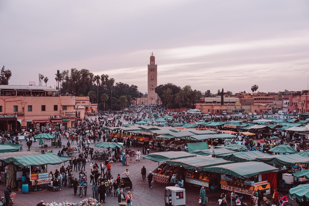 Lit Marrakech medina street at night — lanterns and warm glow on ochre walls, a safe main artery