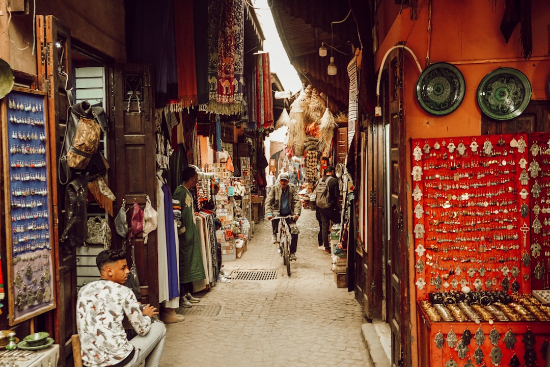 Marrakech souk alley — hanging brass lanterns and spice stalls under dappled light in the medina