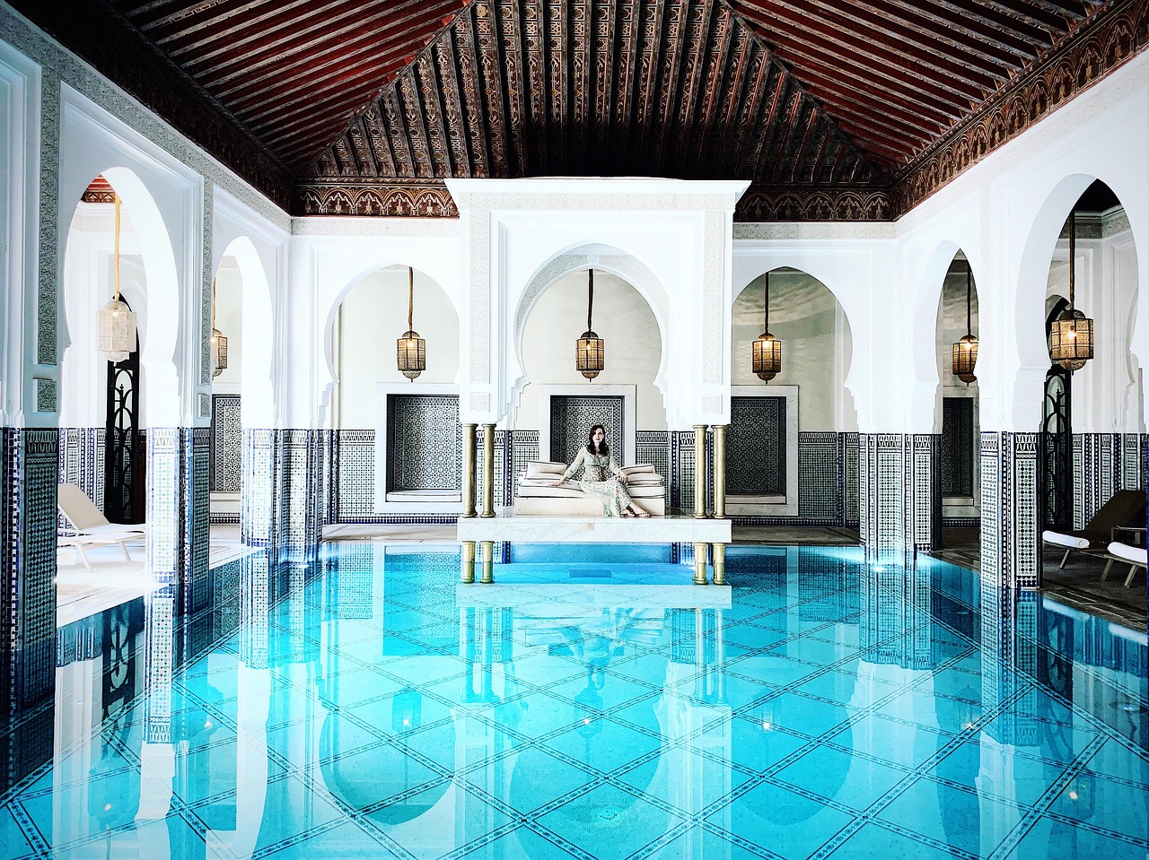 Tranquil riad spa hammam in Morocco β candlelit zellige-tiled room with rose petals on warm marble and folded towels