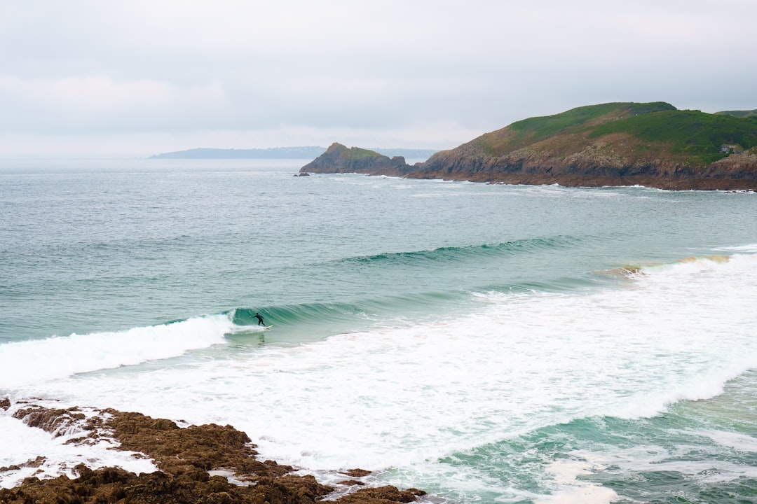 Morocco surf season - a surfer checking the swell at dawn from a rocky headland with lined-up Atlantic waves behind